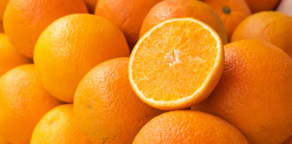 Orange coupée en deux posée sur de nombreuses autres oranges empilées