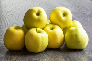 Pommes jaunes posées sur une table en bois foncé