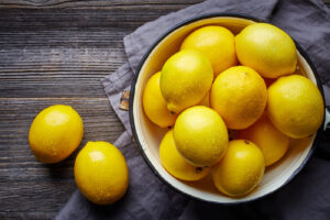 citrons disposés dans un bol ainsi que sur une table en bois foncé